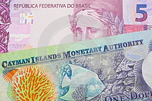 A pink and purple five real bank note from Brazil paired with a colorful one dollar note from the Cayman Islands.