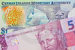 A pink and purple five real bank note from Brazil paired with a colorful one dollar note from the Cayman Islands.