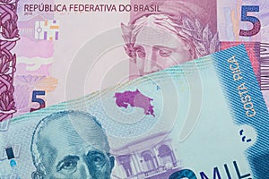 A pink and purple five real bank note from Brazil paired with a colorful two thousand colones bank note from Costa Rica.