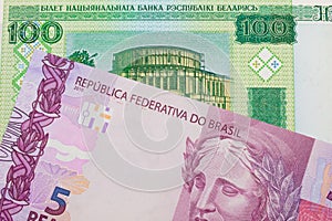 A pink and purple five real bank note from Brazil paired with a green one hundred ruble note from Belarus.