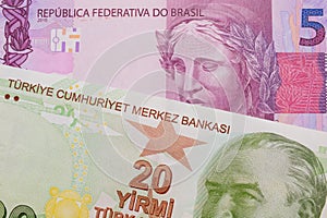 A pink and purple five real bank note from Brazil paired with a green, twenty Turkish lira bank note.