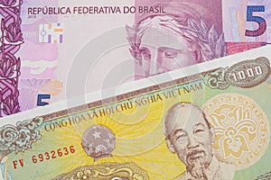 A pink and purple five real bank note from Brazil paired with a yellow one thousand dong bill from Vietnam.