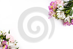 Pink and purple gillyflowers with alstroemeria on white background, flat lay