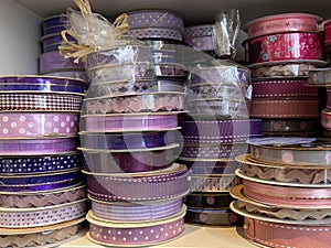 Pink and purple gingham and polka dot ribbons rolls on display in haberdashery sewing shop