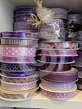 Pink and purple gingham and polka dot ribbons rolls on display in haberdashery sewing shop