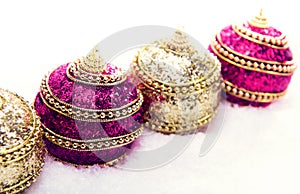 Pink and purple and gold Christmas balls in snow with tinsel, christmas background