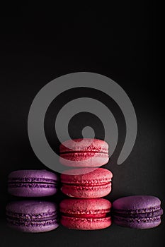 Pink and purple macaroons on a dark background. International Women`s Day. French national cuisine. Food shot. closeup