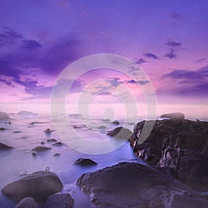 Pink and Purple Sunset Over Misty Rocks in the Sea