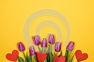 Pink, purple tulips and red hearts on yellow background on bottom with space