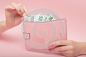 Pink purse and Euro banknotes in Female hands on pink background. Business Concept and Instagram