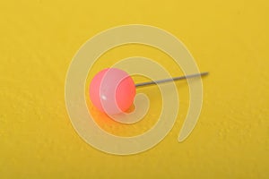 Pink pushpin isolated on a yellow background