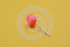 Pink pushpin isolated on a yellow background
