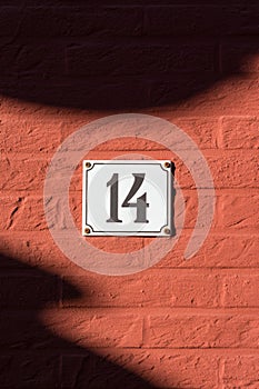 White house number plate 14 on red wall photo