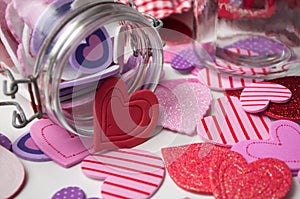 Pink and red hearts falling from glass container on white background - valentine`s day concept