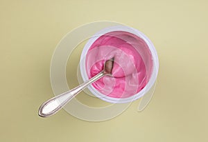 Pink red velvet flavour yogurt in plastic cup isolated on yellow pastel background with space for text photo