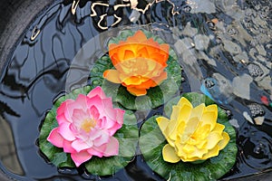 Pink, red and yellow artificial lotus flower in the water, garden decoration element