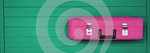 Pink retro suitcases on the wooden green background