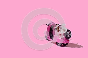 Pink retro toy bike delivering bouquet of flowers box on pink background. February 14 card,