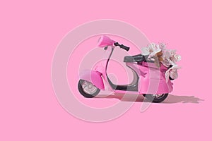 Pink retro toy bike delivering bouquet of flowers box on pink background. February 14 card, Valentine`s day. Flower delivery.