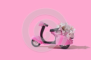 Pink retro toy bike delivering bouquet of flowers on pink background. February 14 card, Valentine`s day. Flower delivery. 8 March
