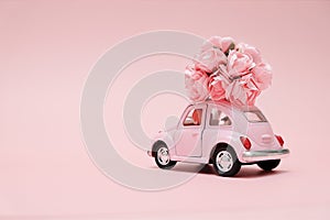 Pink retro toy car delivering bouquet on pink background. February 14, Valentine`s day.. 8 March, International Happy Women`s Day.