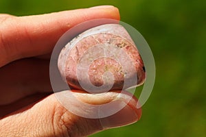 Pink Rhodonite rock from South Africa held in a hand