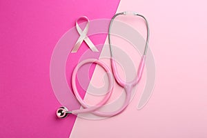 Pink ribbon as breast cancer awareness symbol and stethoscope on color background