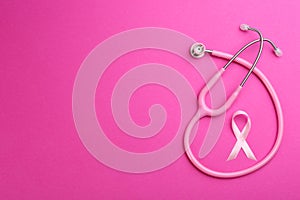 Pink ribbon as breast cancer awareness symbol and stethoscope on color background, flat lay