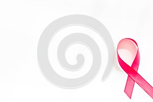 Pink ribbon as symbol of breast cancer awareness on white background top view space for text