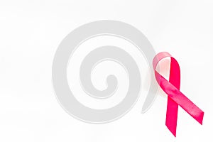 Pink ribbon as symbol of breast cancer awareness on white background top view space for text