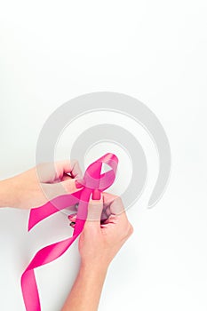 Pink ribbon background. Health care symbol pink ribbon in woman hands on white background. Breast cancer support concept