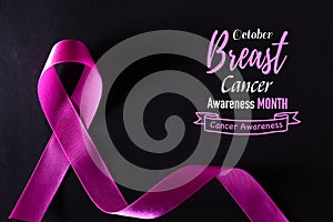 Pink ribbon on black paper background for supporting breast cancer awareness month campaign
