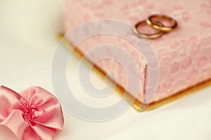 Pink ribbon bow with a gift box and wedding rings
