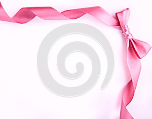 Pink ribbon with bow on the white background