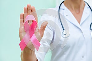 Pink ribbon for breast cancer awareness in doctor`s hand, women breast tumor illness campaign
