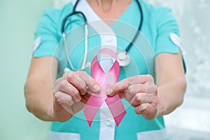 Pink ribbon for breast cancer awareness in doctor`s hands, women breast tumor illness campaign