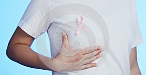 Pink ribbon, breast cancer and awareness with a woman in studio on a blue background for health. Chest, medical and