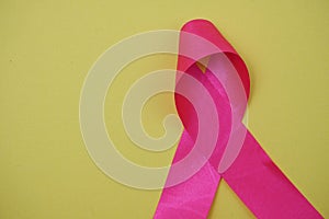 Pink ribbon breast cancer awareness on yellow background