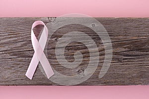 Pink ribbon breast cancer on wooden background. Top view