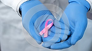 Pink ribbon in doctors hands, breast cancer awareness and prevention campaign