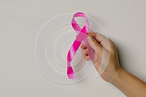 Pink ribbon in hand, symbol of breast cancer awareness