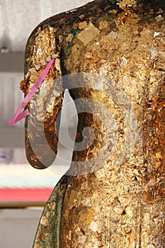 A pink ribbon is hooked to the hand of a statue of Buddha (Thailand)