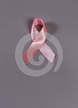 Pink ribbon isolated on grey, top view. Defocus, copy space