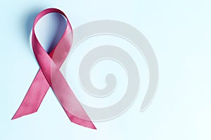 Pink ribbon on light blue background, breast cancer concept