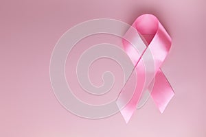 Pink ribbon on pink background as symbol of female breast disease. Breast cancer month awareness tape. Minimalistic