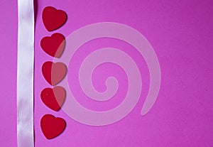 Pink ribbon and red hearts on pink background. Valentines day background.