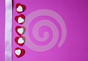 Pink ribbon and red and white hearts on pink background. Valentines day background.