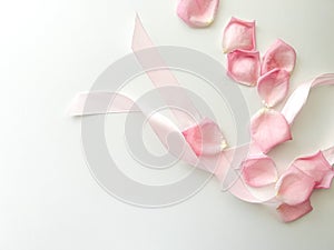 Pink ribbon and rose petals on a light background. Place for text. Gift for Valentine's Day, Mother's Day, Birthday