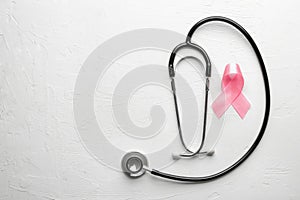 Pink ribbon and stethoscope on light background. Breast cancer awareness concept