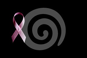 Pink ribbon, a symbol of breast cancer awareness, isolated on a black background. space for text